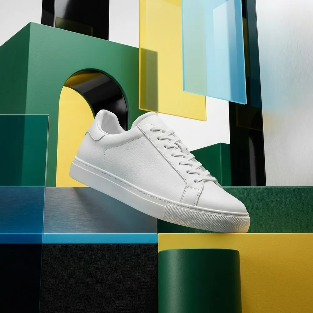 White sneaker, three-quarter view, on a geometric set